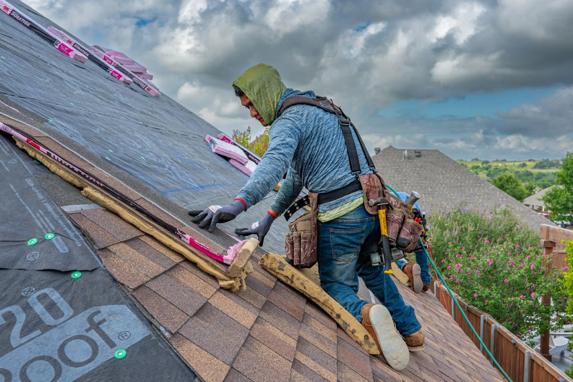 A roofer carrying materials across a residential roof under construction