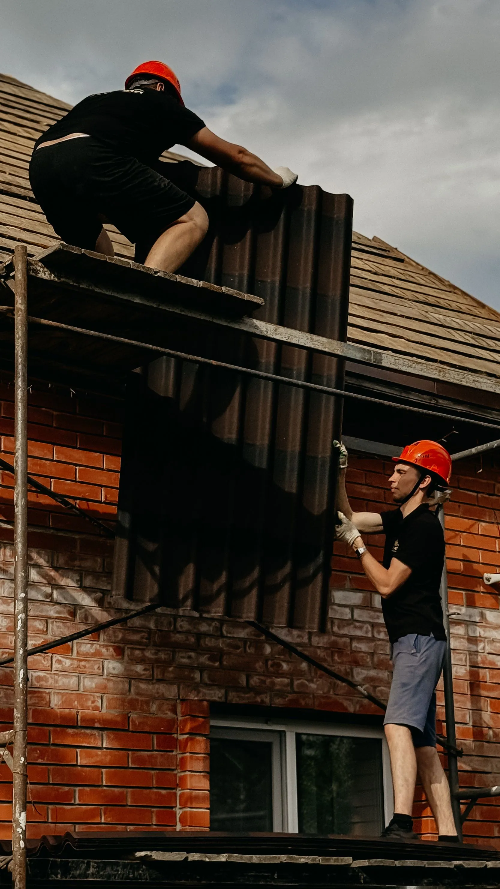 A roofing crew member working at the edge of a residential roof