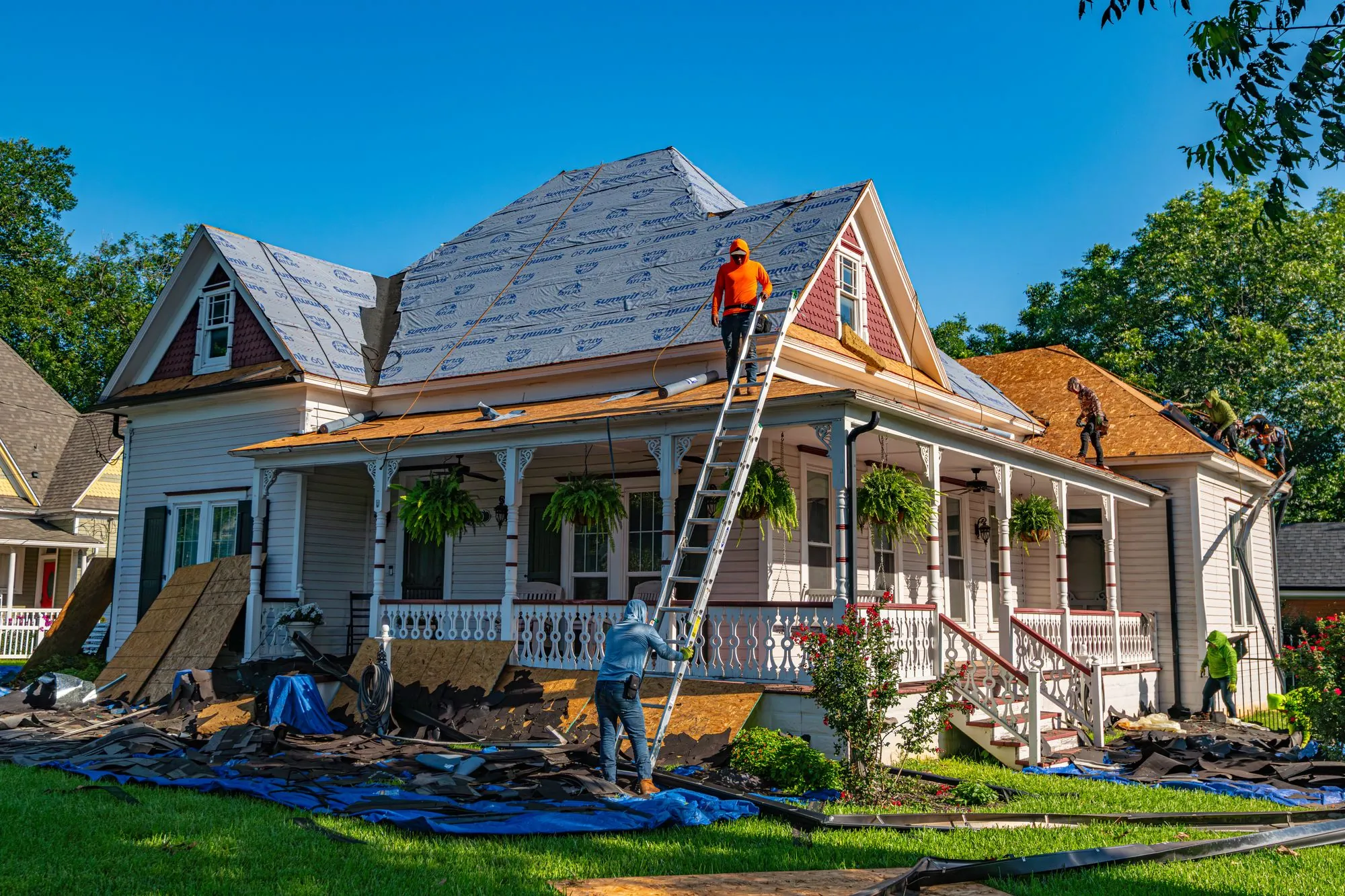 Roofing crew working across a residential roof deck under open sky
