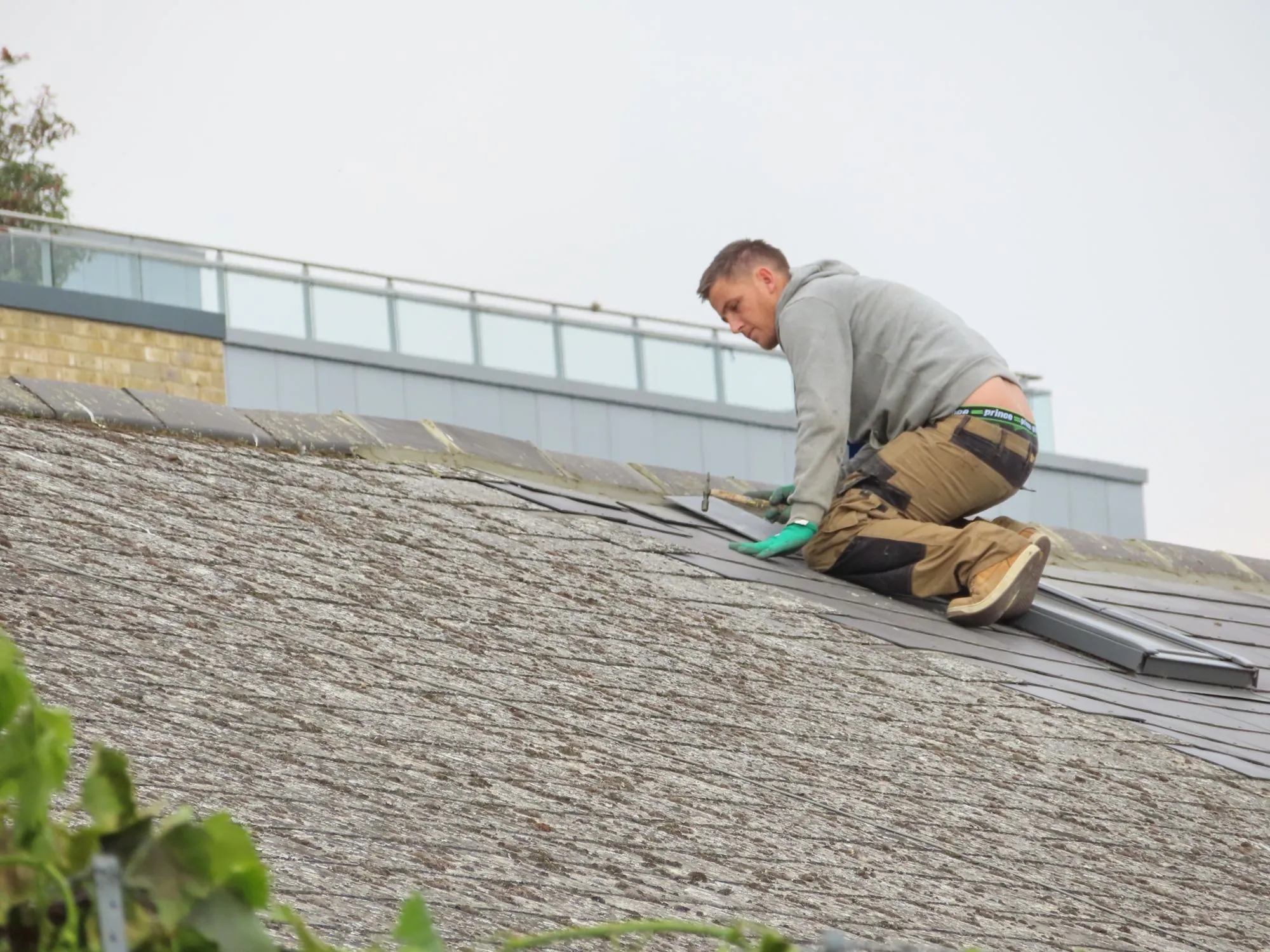 A roofer carrying out a shingle repair on a residential roof